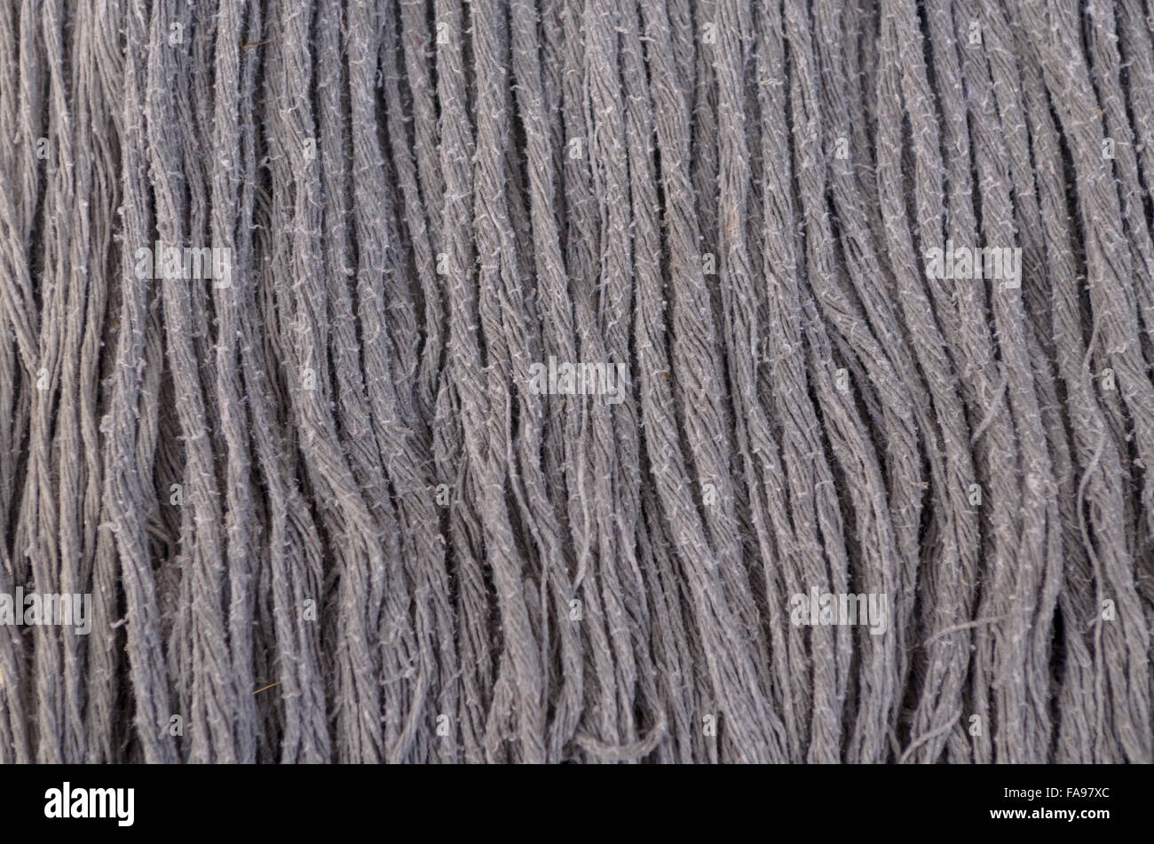 Panno vecchio mop giace contro una parete texture di sfondo. Foto Stock