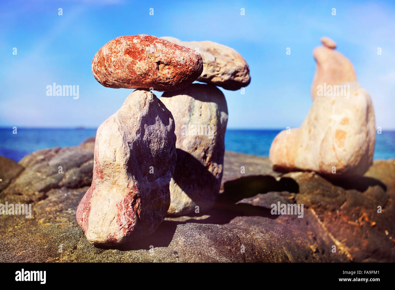 Primo piano di alcune pile di pietre equilibrato in Isola di Ibiza in Spagna, con il mare Mediterraneo e in background Foto Stock