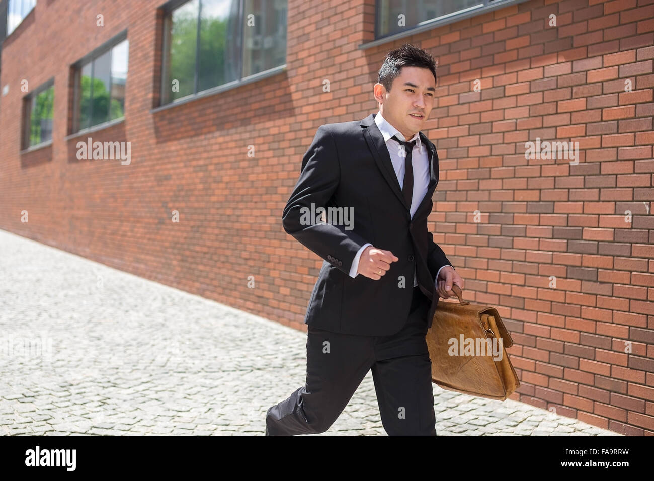 Il cinese giovane imprenditore in esecuzione in una strada di città Foto Stock Il cinese giovane imprenditore in esecuzione in una strada di città Foto Stock