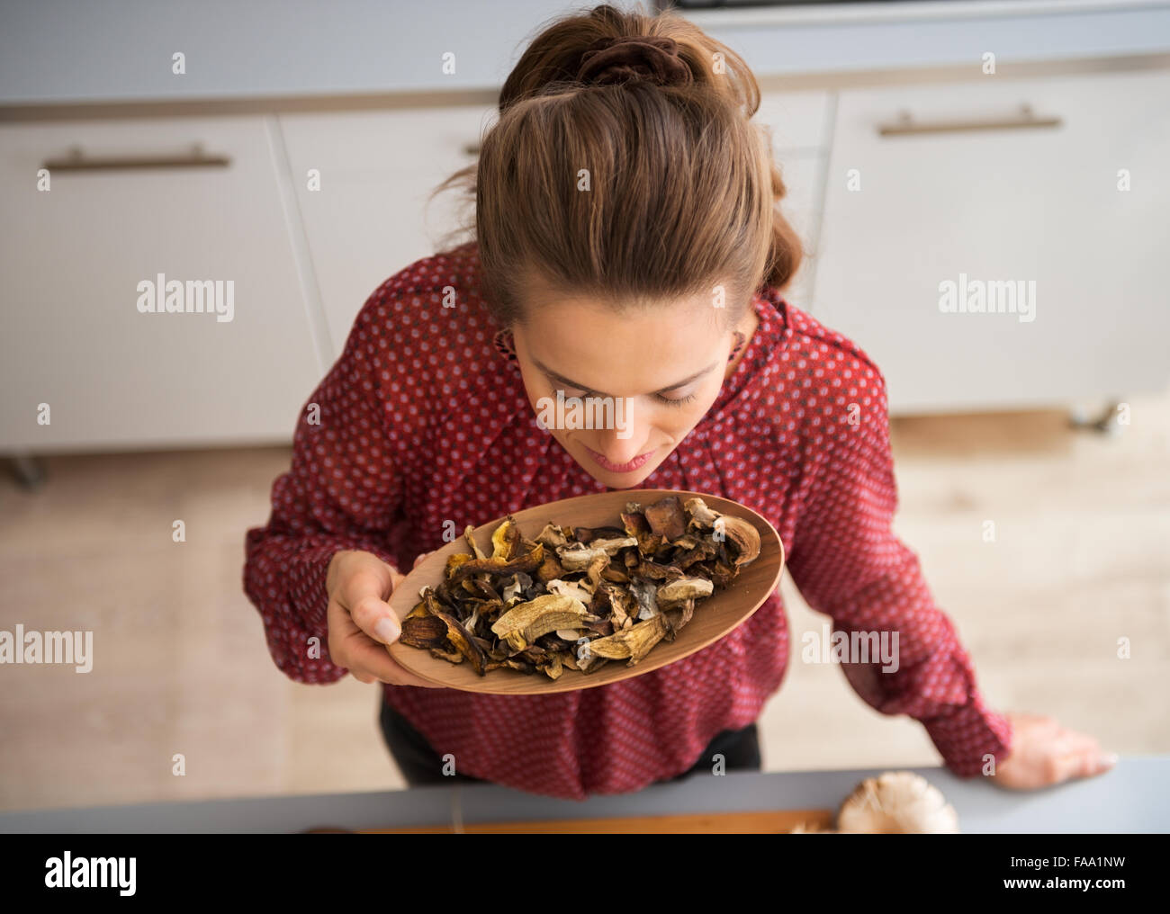 Visto dal di sopra, una donna è in piedi, la respirazione nel ricco, terra odore di funghi secchi come essa si erge in una cucina. Foto Stock