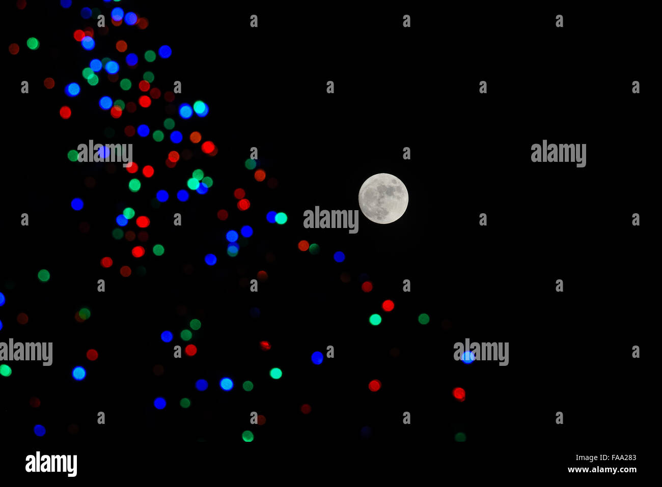 Una luna piena accanto a albero di Natale luci nel cielo notturno alla vigilia di Natale. Foto Stock