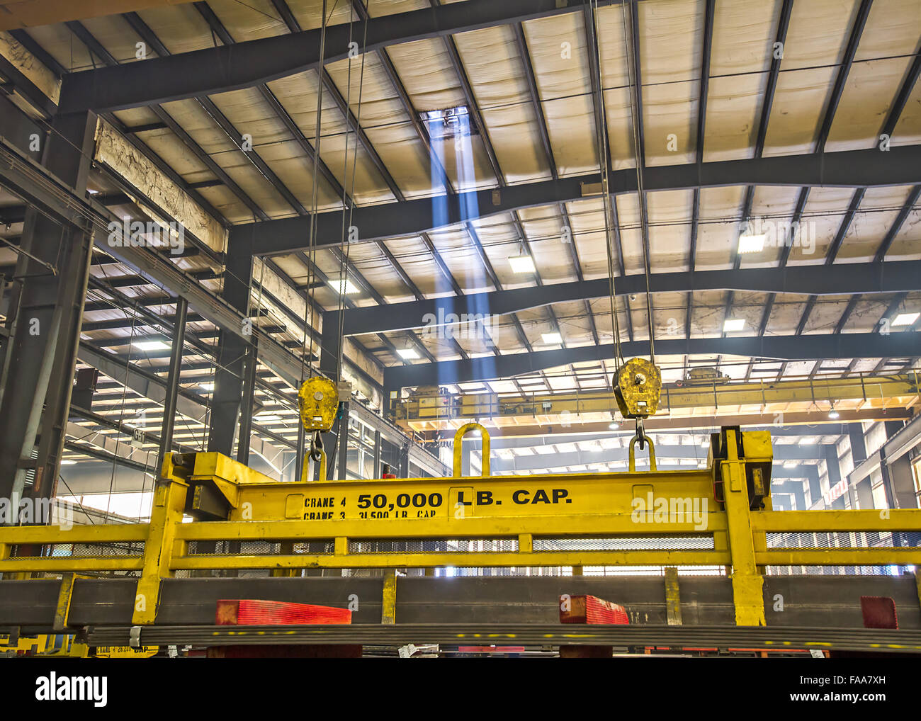 Raggi di sole lo streaming attraverso il lucernario su 50 ton gru tenendo le piastre in acciaio all'interno di fabbrica Foto Stock