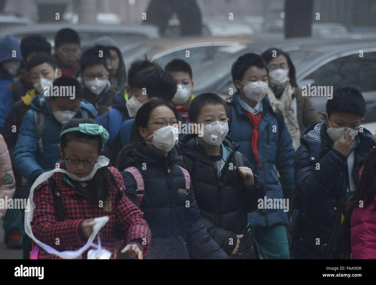 Pechino, Cina. 25 Dic, 2015. Gli studenti indossare maschere a piedi su un smog avvolta street per un evento scolastico a Pechino, 25 dicembre, 2015. Un allarme arancione è stato rilasciato per avvisare lo smog e inquinamento atmosferico dal locale ufficio meteorologico a Pechino il venerdì mattina. Credito: Wu Wei/Xinhua/Alamy Live News Foto Stock