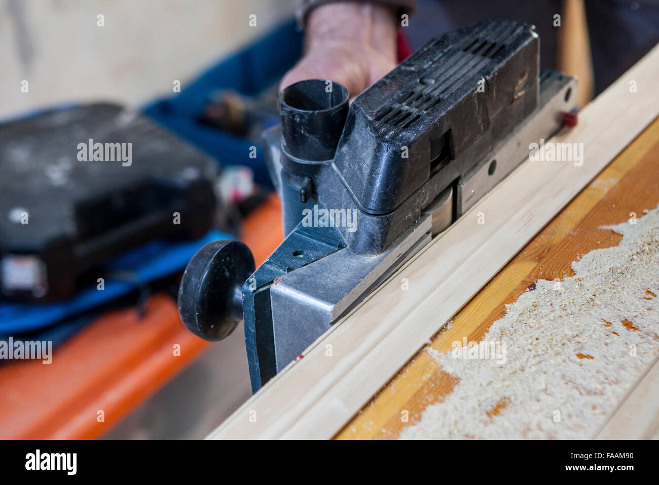 Carpenter lavora con i montanti delle porte tramite presa elettrica piano Foto Stock