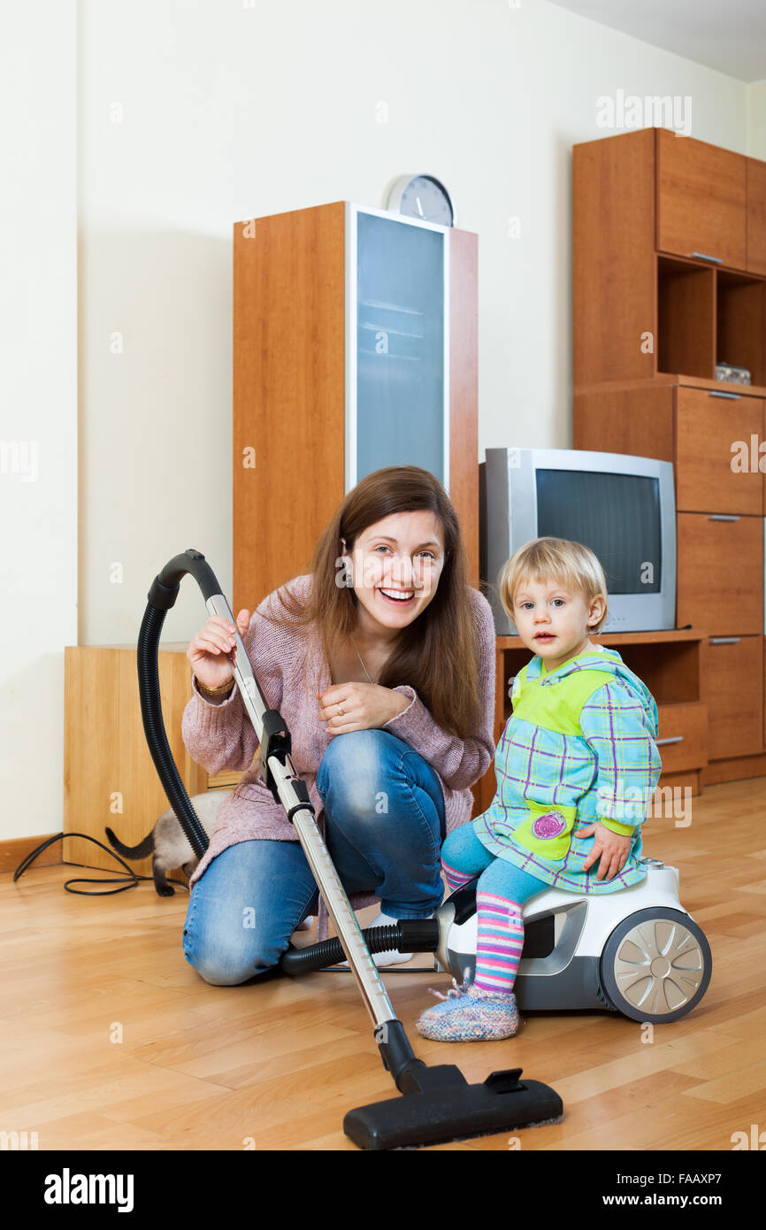 Sorridenti giovane madre e bambino con un aspirapolvere Foto Stock