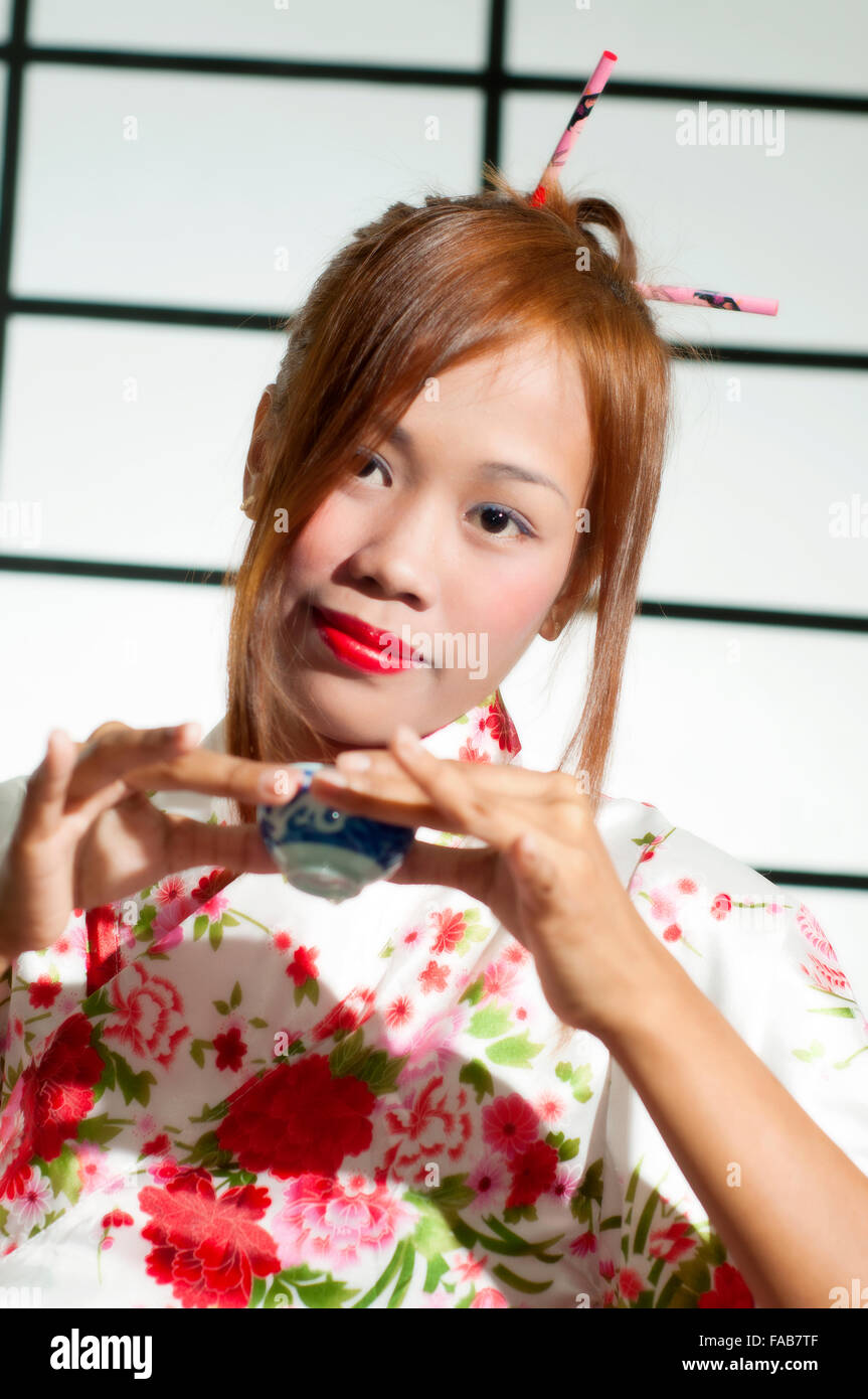 Giovane donna giapponese bere il tè in ambienti chiusi in studio di impostazione Foto Stock