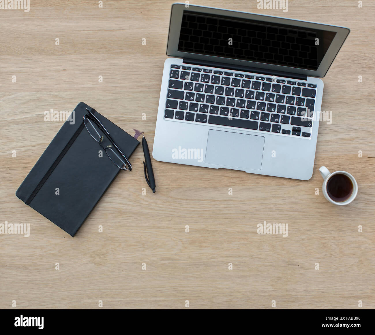 Laptop, notebook con penna, occhiali e la tazza di caffè, giacente sul tavolo di legno di quercia. Foto Stock