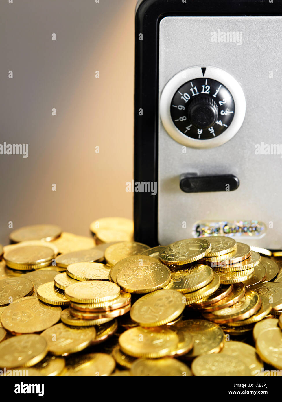 Monete di fronte al mini cassetta di sicurezza Foto Stock