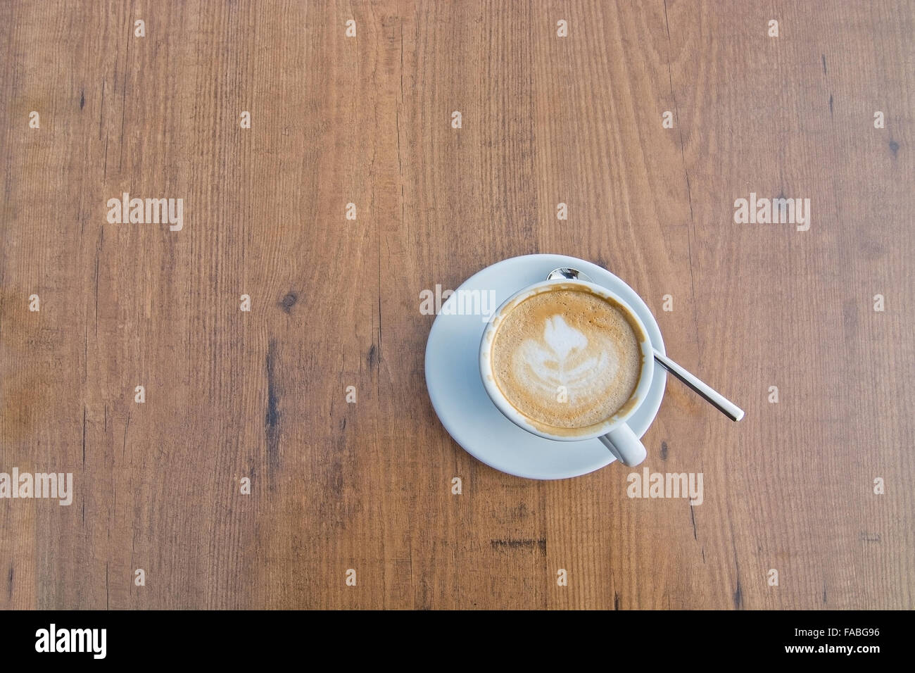 Tazza bianca con la formazione di schiuma cappuccino e caffè cucchiaio sul tavolo di legno vista aerea Foto Stock