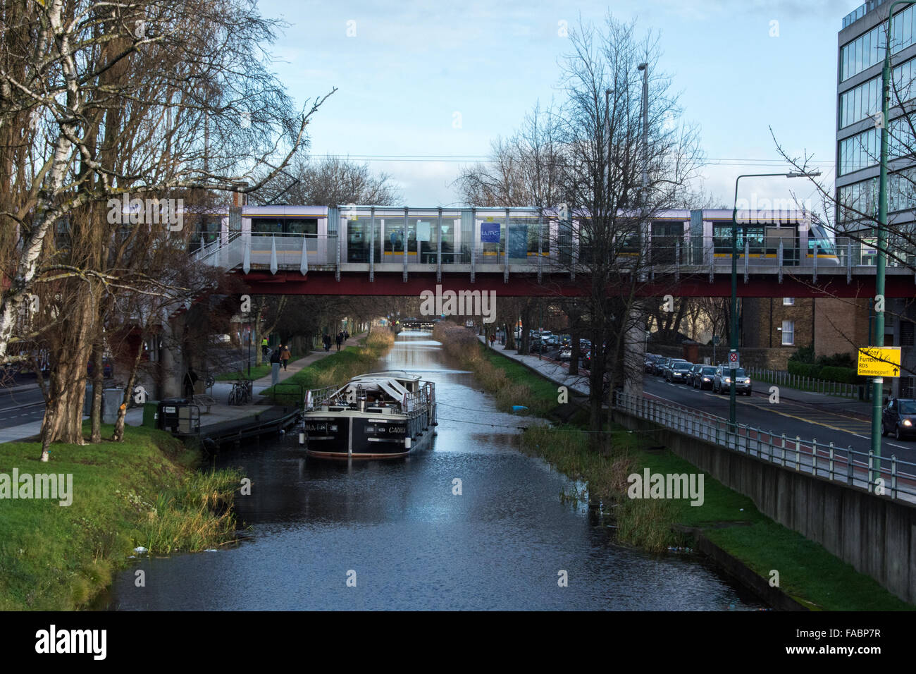 Il Canal Grande nel centro di Dublino con una chiatta e il Luas LRT su un ponte Foto Stock