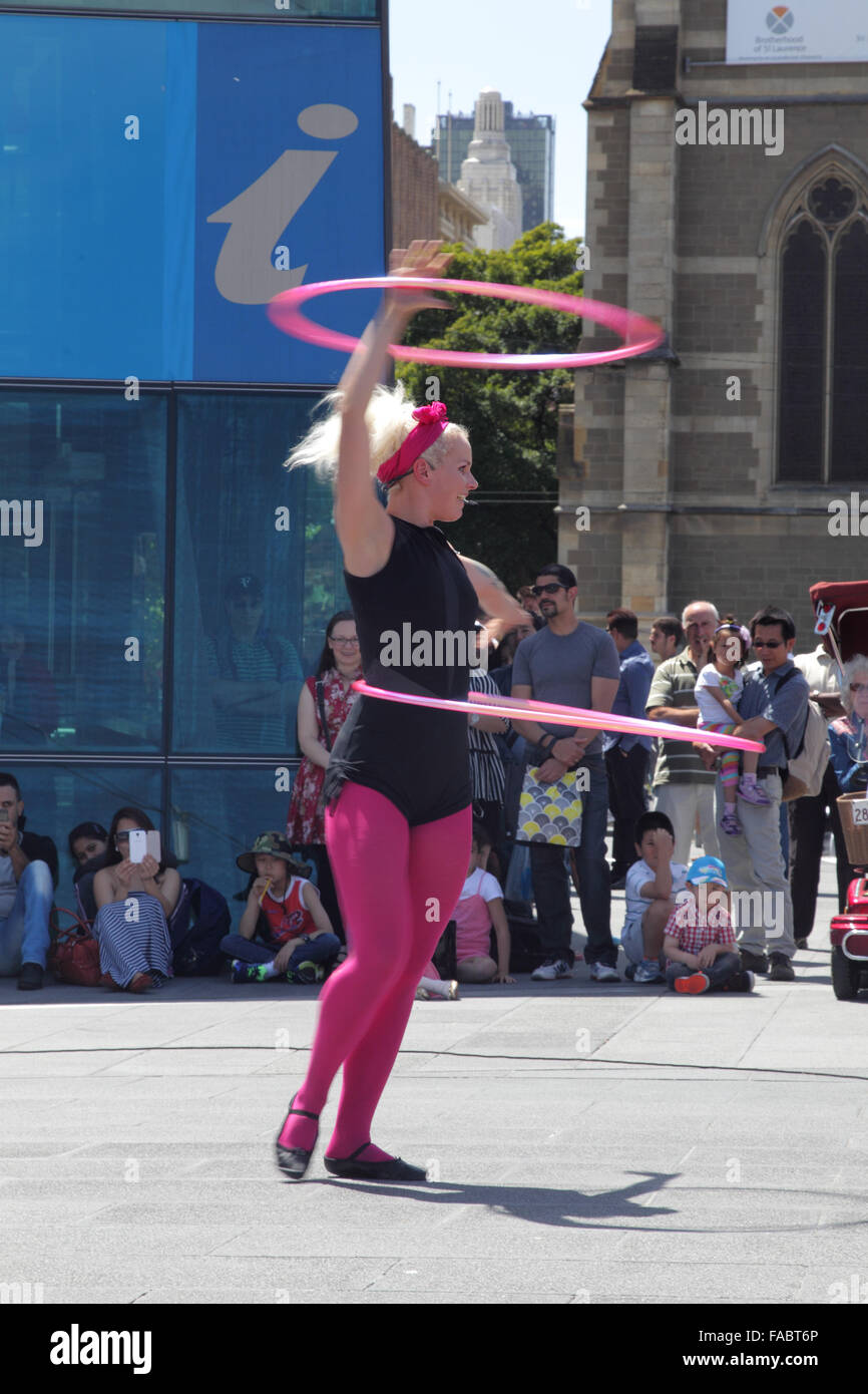 Street performer che mostra un-hula hoop le prestazioni su Federation Square a Melbourne, Victoria, Australia, su una soleggiata giornata estiva. Foto Stock