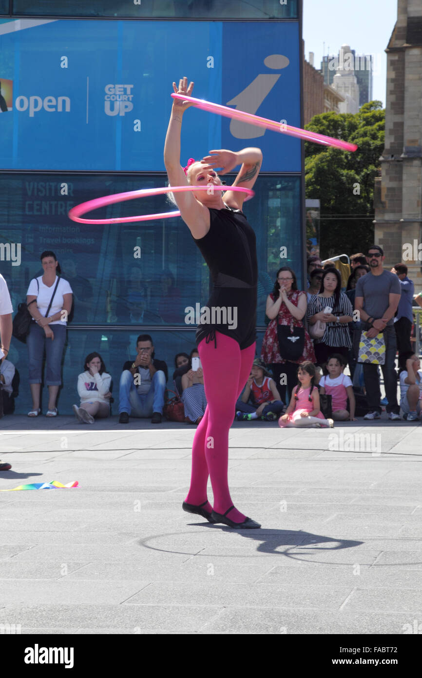 Street performer che mostra un-hula hoop le prestazioni su Federation Square a Melbourne, Victoria, Australia, su una soleggiata giornata estiva. Foto Stock