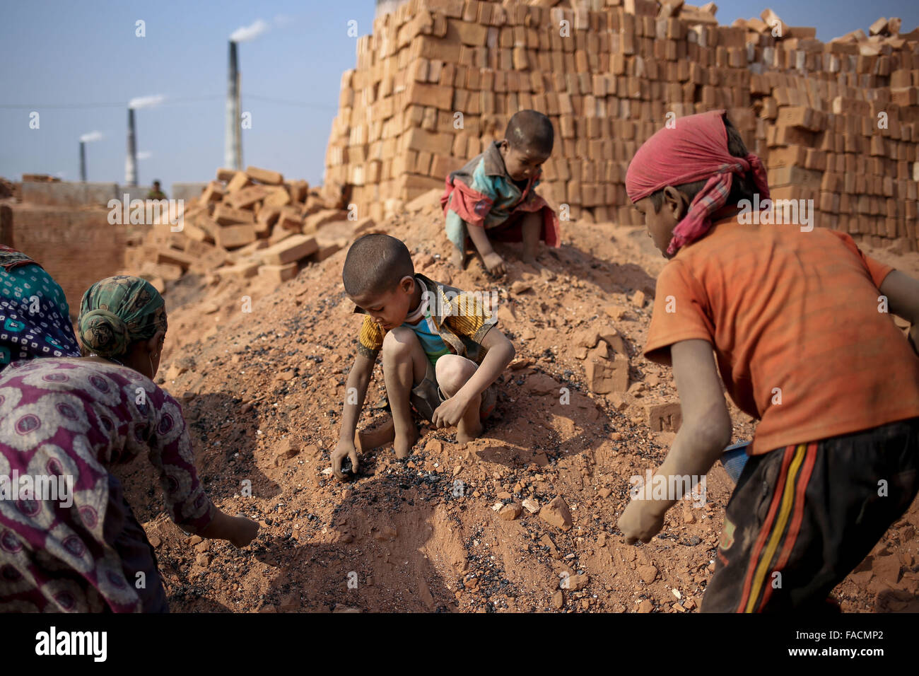 Dacca in Bangladesh. 27 Dic, 2015. I bambini sono la ricerca di carbone proveniente da più di sinistra di cenere. Essi le vendite ogni sacchetto del carbone a 2,5$ al mattone cantiere proprietario. Il mondo sta attraversando una rapida urbanizzazione e il Bangladesh non è un'eccezione da questo. Tale rapida urbanizzazione genera una massiccia domanda per mattoni come esso è uno degli ingredienti chiave per la creazione di struttura in calcestruzzo. Per soddisfare questa necessità crescente, i numeri del mattone facendo campo sono state aumentando ad un ritmo allarmante in Bangladesh. La maggior parte di essi ha avuto luogo in terre agricole che provoca la riduzione della produzione agricola. Foto Stock