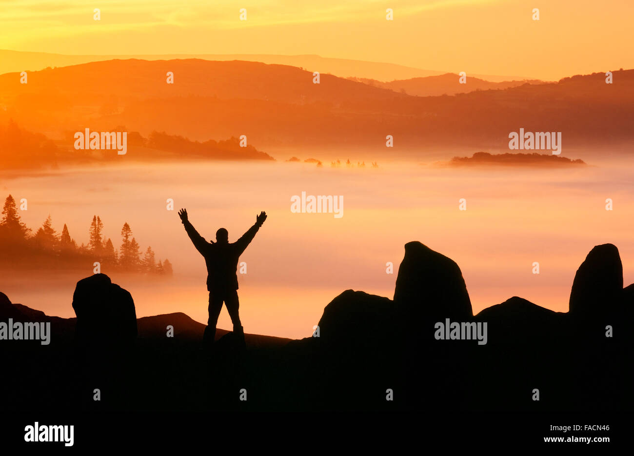 Nebbia a valle sul Lago di Windermere da Todd roccioso nel distretto del lago, Regno Unito all'alba con un profilarsi l'uomo. Foto Stock
