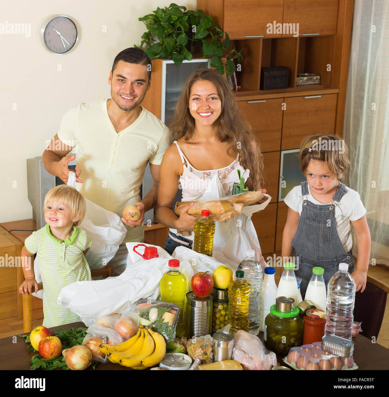 Allegro famiglia di quattro persone con sacchi di cibo in appartamento Foto Stock