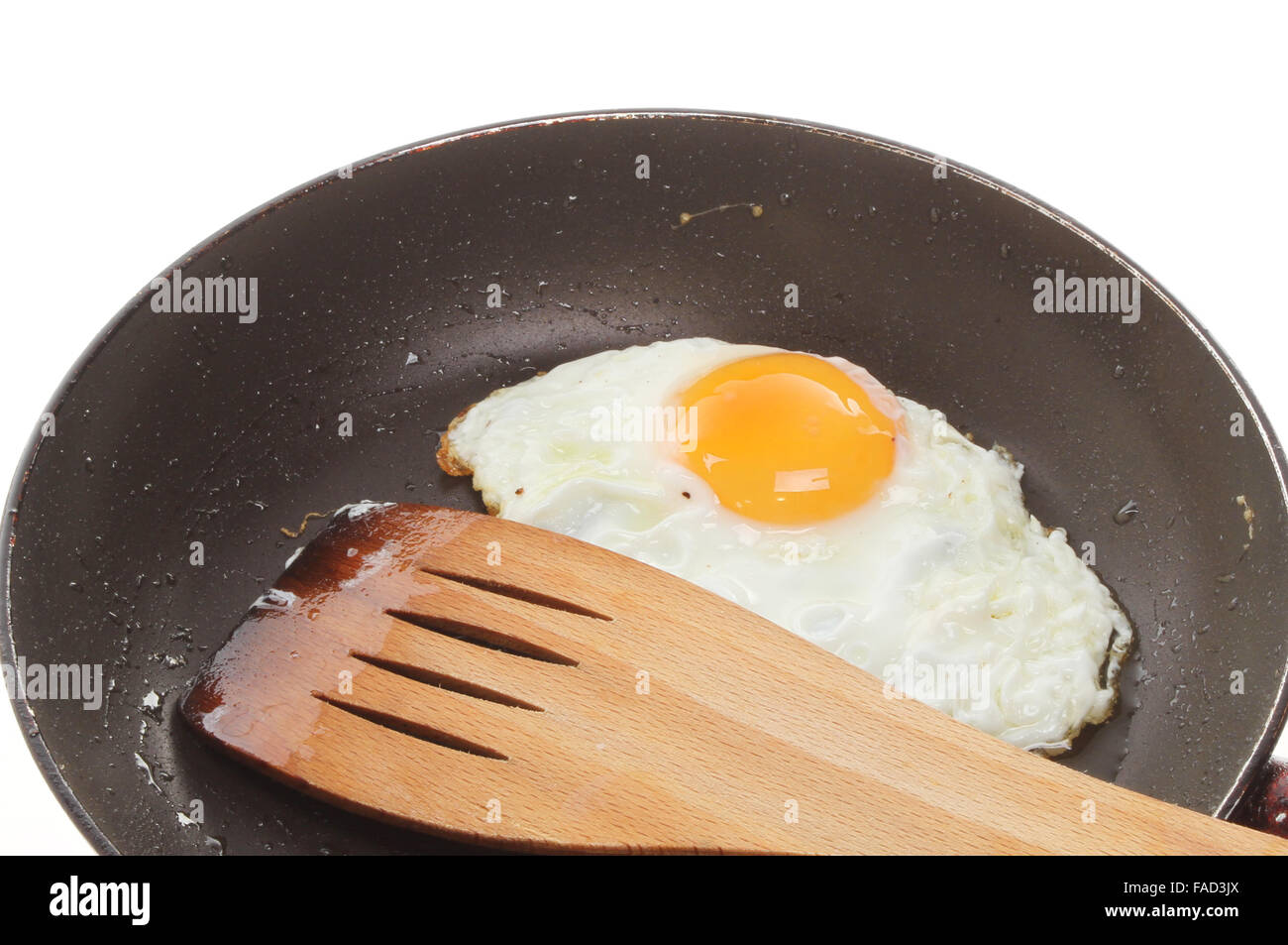 Primo piano di un uovo fritto con una spatola di legno in una padella Foto Stock