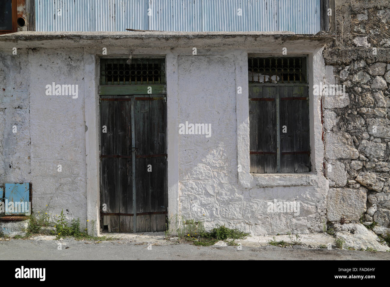 Vecchia porta verde e nella finestra imposta su un abbandonato Greco bianco casa di villaggio. Foto Stock