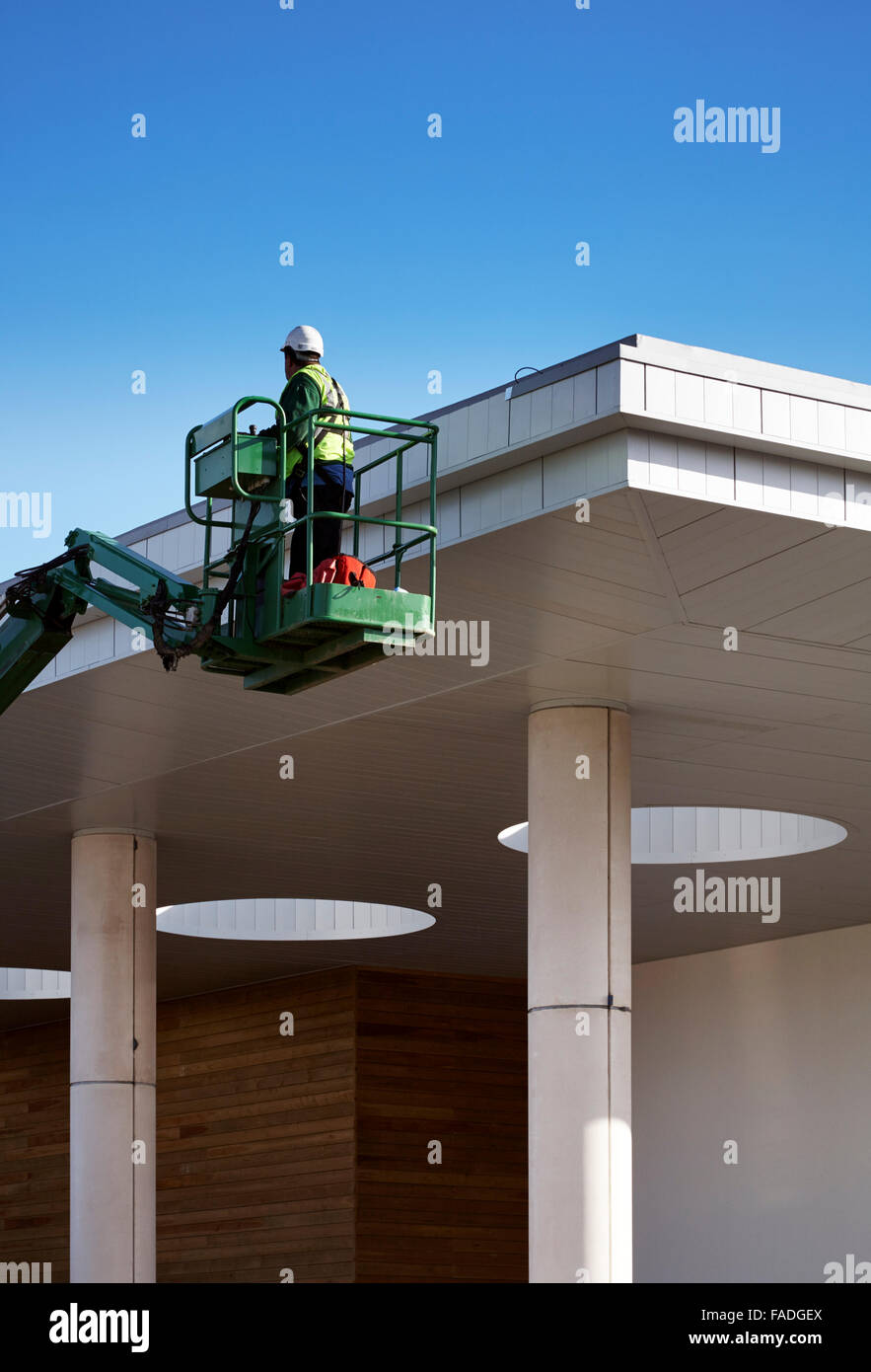Operaio edile utilizza cherry picker per raggiungere il tetto di un edificio in costruzione a Huddersfield Leisure Centre copia spazio per il testo Foto Stock