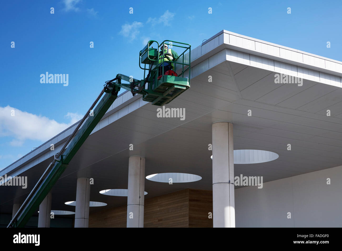 Operaio edile utilizza cherry picker per raggiungere il tetto di un edificio in costruzione a Huddersfield Leisure Centre copia spazio per il testo Foto Stock
