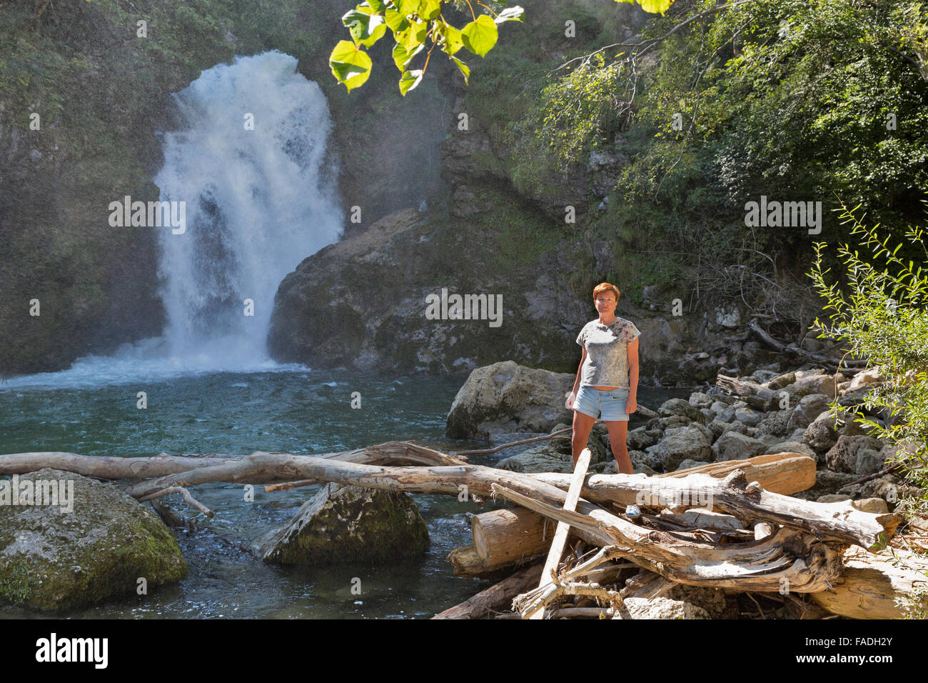 Persone di mezza età abbronzata donna caucasica si erge di fronte a cascata di Somma. Gola Gorge, il parco nazionale del Triglav in Slovenia Foto Stock