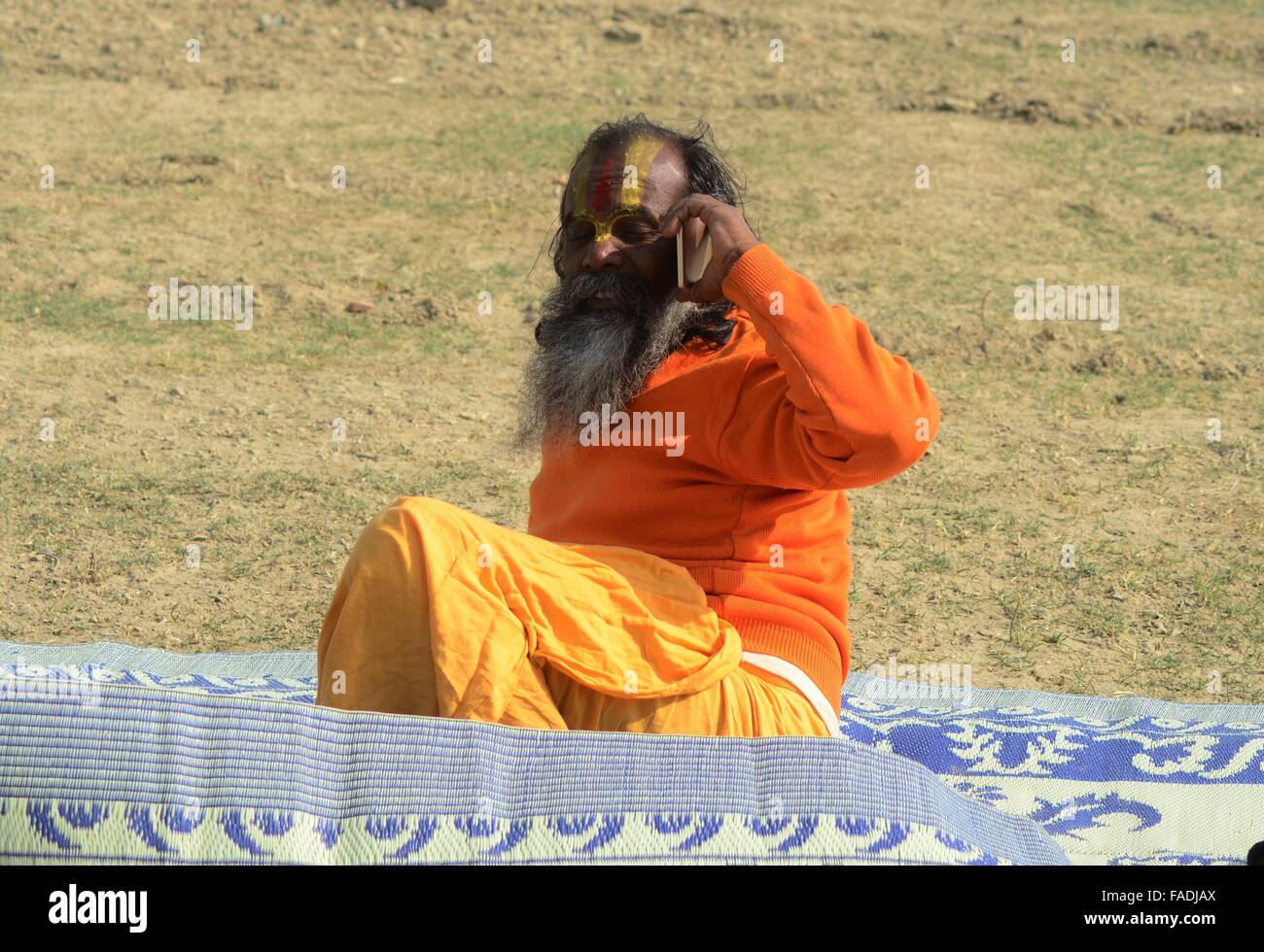 Di Allahabad, Uttar Pradesh, India. 28 dicembre, 2015. India, Uttar Pradesh, di Allahabad: un sadhu talk su mobile dopo arrivare a frequentare Magh mela fiera alla banca di Sangam, alla confluenza del fiume Ganga Yamuna e saraswati mitologica in Allahabad il 28 dicembre, 2015. Il Magh Mela si svolge ogni anno sulle rive del Triveni Sangam - la confluenza dei tre grandi fiumi Ganga, Yamuna e la mistica Saraswati durante il mese indù di Magh che corrisponde a metà gennaio - metà febbraio. © Prabhat Kumar Verma/ZUMA filo/Alamy Live News Foto Stock