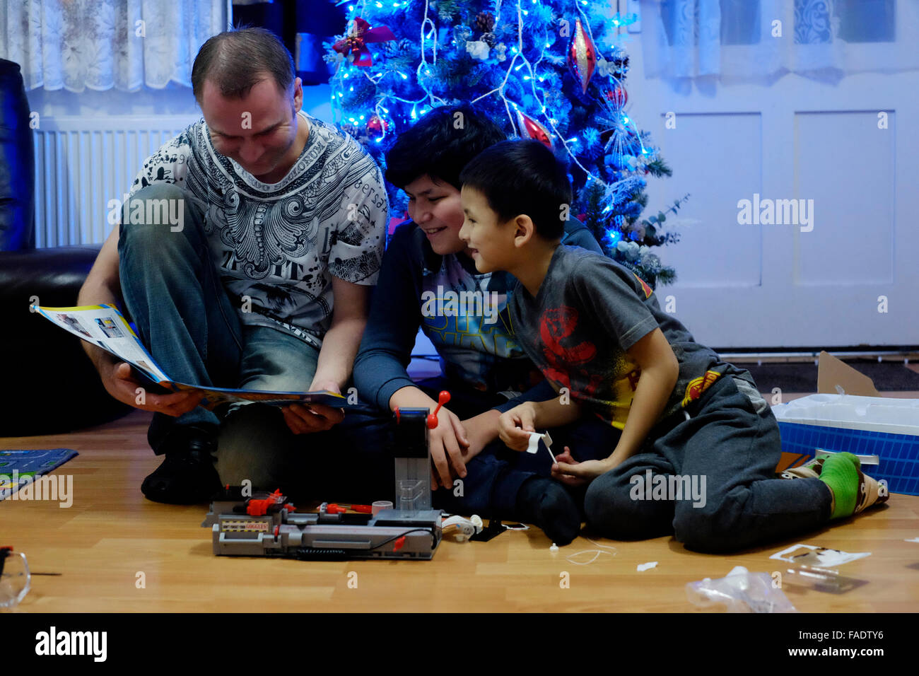 Giovane famiglia a Natale guardando al bambino il dono con albero dietro Foto Stock