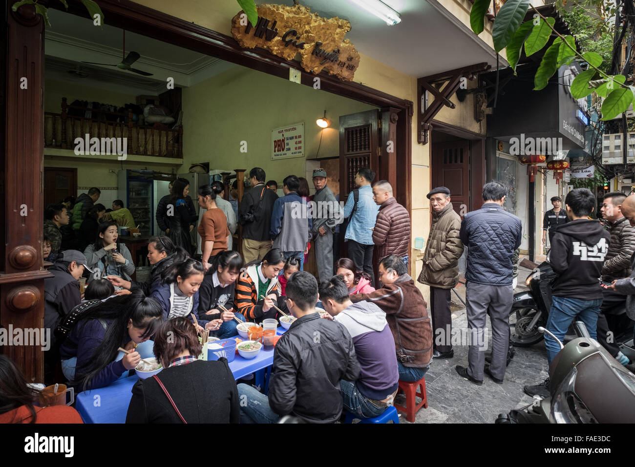 La gente in coda per il loro campo di bocce di Pho Bo (carni bovine noodle soup) all'iconico Pho Gia Truyen a 49 Bat Dan nella città vecchia di Hanoi e. Foto Stock