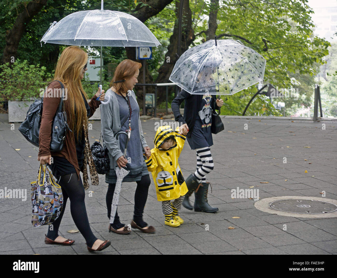 Famiglia giapponese a piedi sotto la pioggia Foto Stock