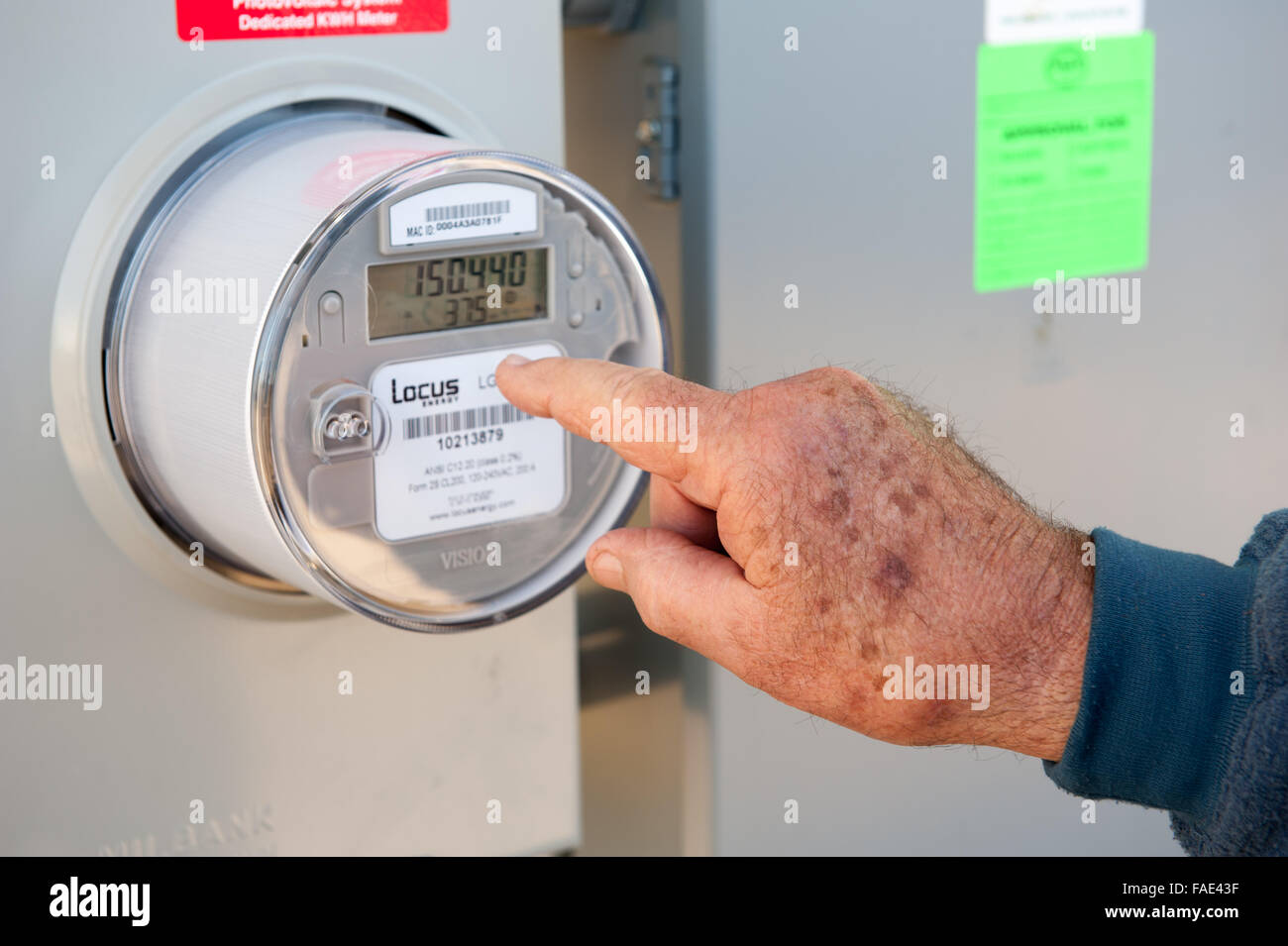 Mano d'uomo puntando verso un contatore di energia elettrica Foto Stock