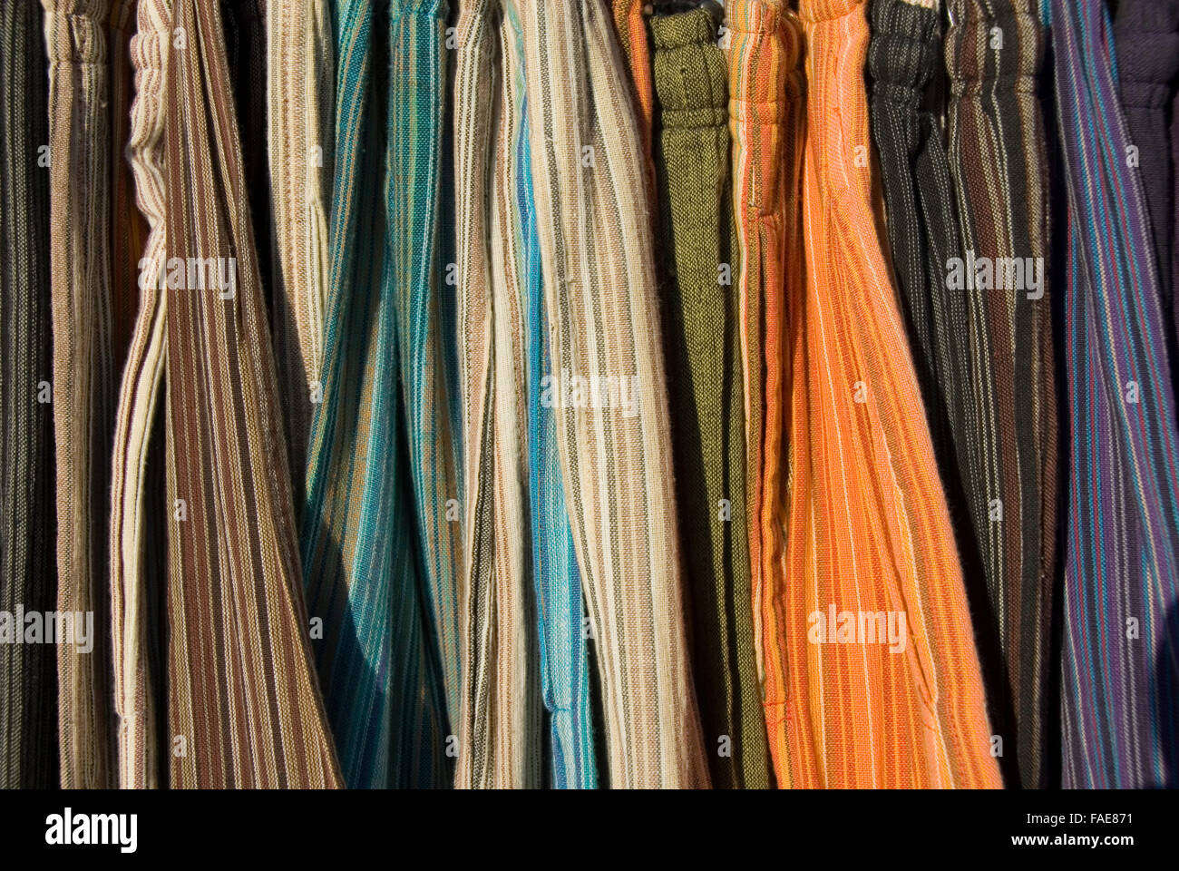 Chiudere fino sulla colorata a strisce di cotone indiano vestiti appesi su una rotaia, in vendita presso la raccolta di verde, Chepstow, Galles Foto Stock