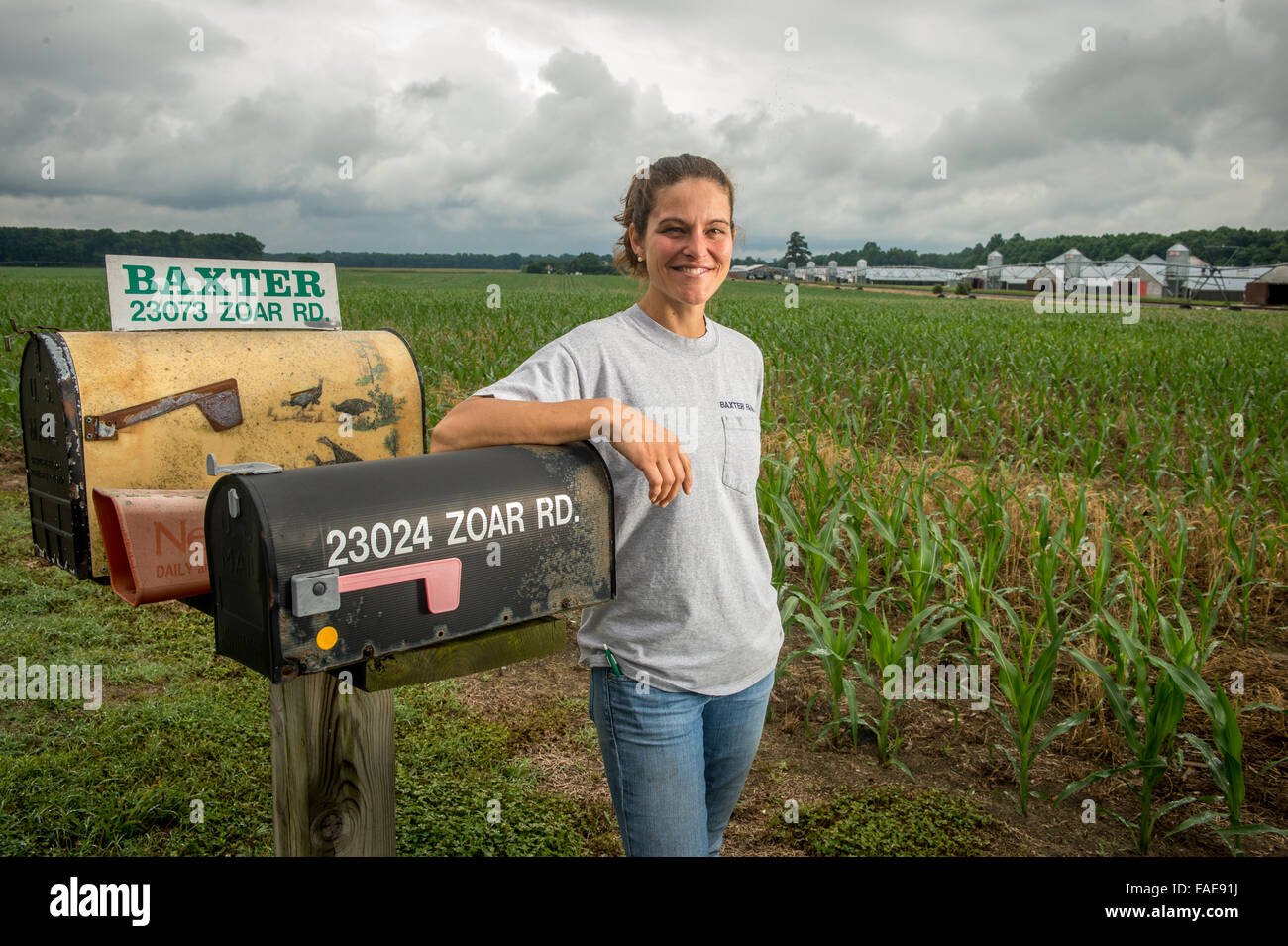 Donna in posa da una cassetta postale per la sua azienda Foto Stock