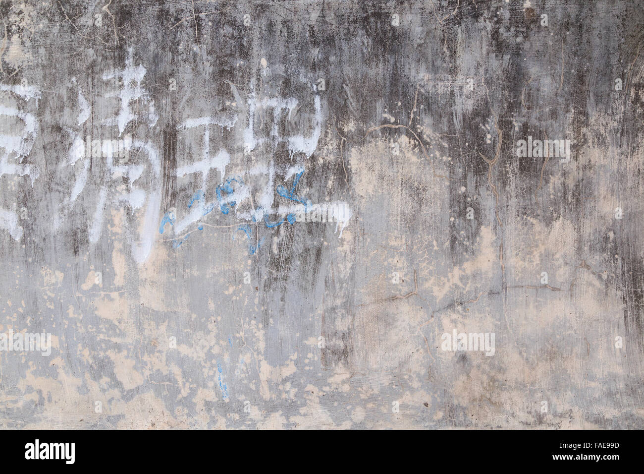 Weathered e invecchiato di cemento grigio texture muro sfondo con alcune sbiadite scrittura cinese. Foto Stock