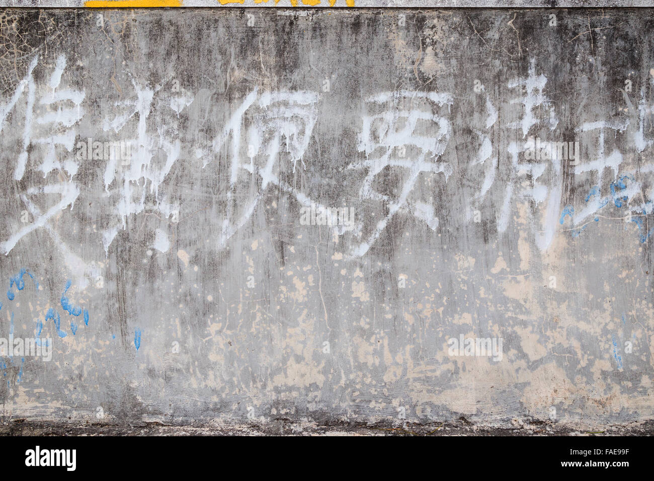 Weathered e invecchiato di cemento grigio texture muro sfondo con vecchie e sbiadite scrittura cinese. Foto Stock
