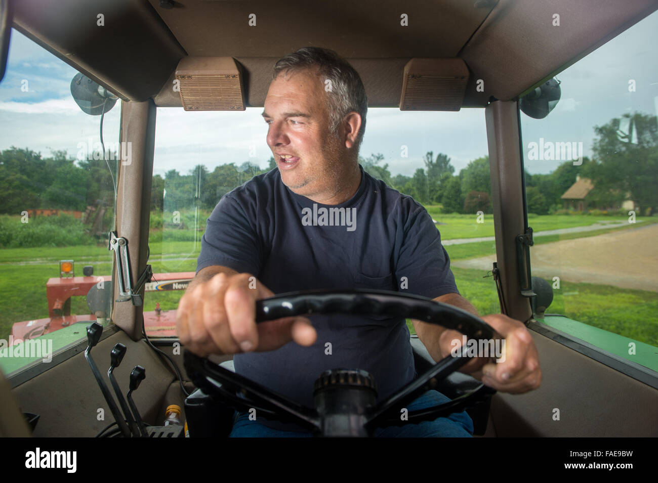 Il contadino alla guida del suo trattore Foto Stock