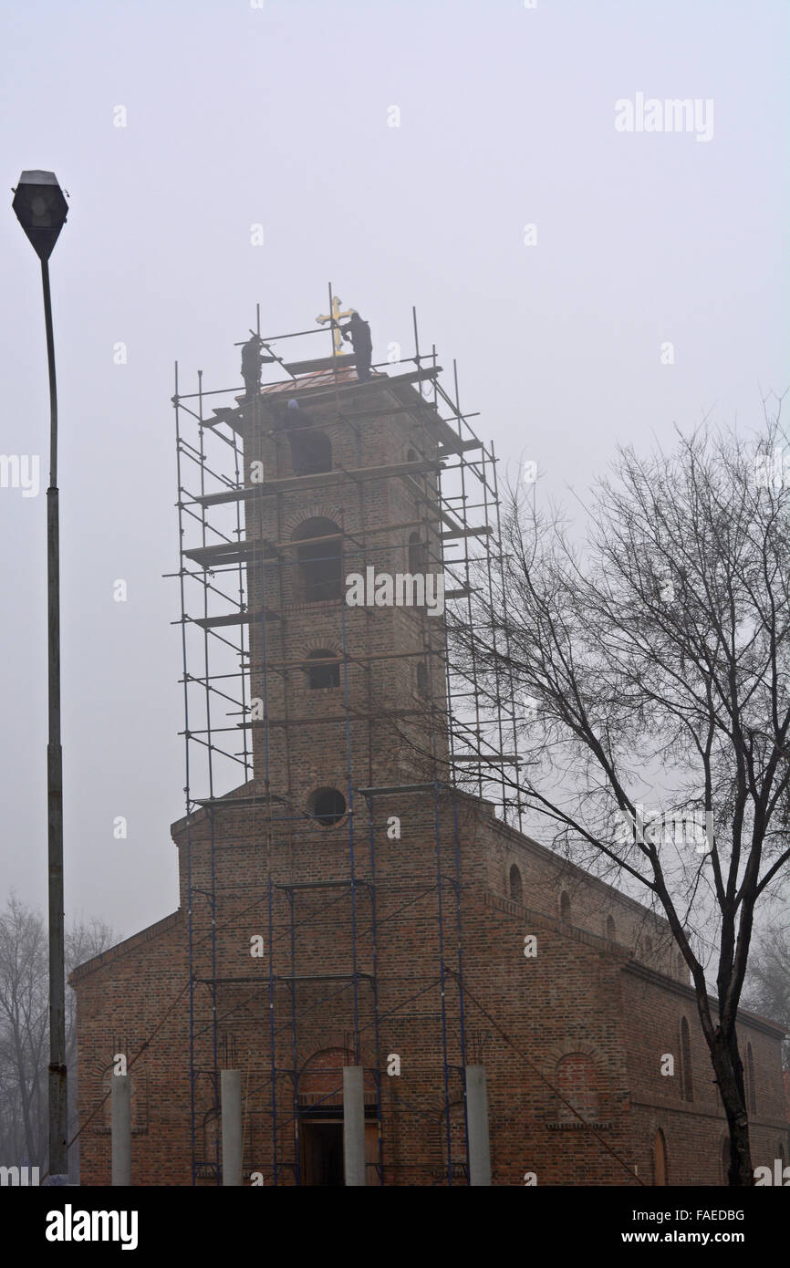 I lavoratori nella nebbia sui lavori di costruzione della nuova chiesa. Foto Stock