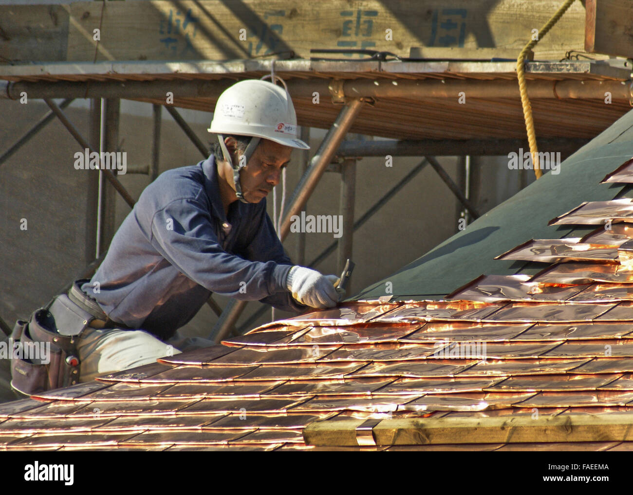 Workman posa in rame nuove tegole del tetto che spiraglio di sole Foto Stock
