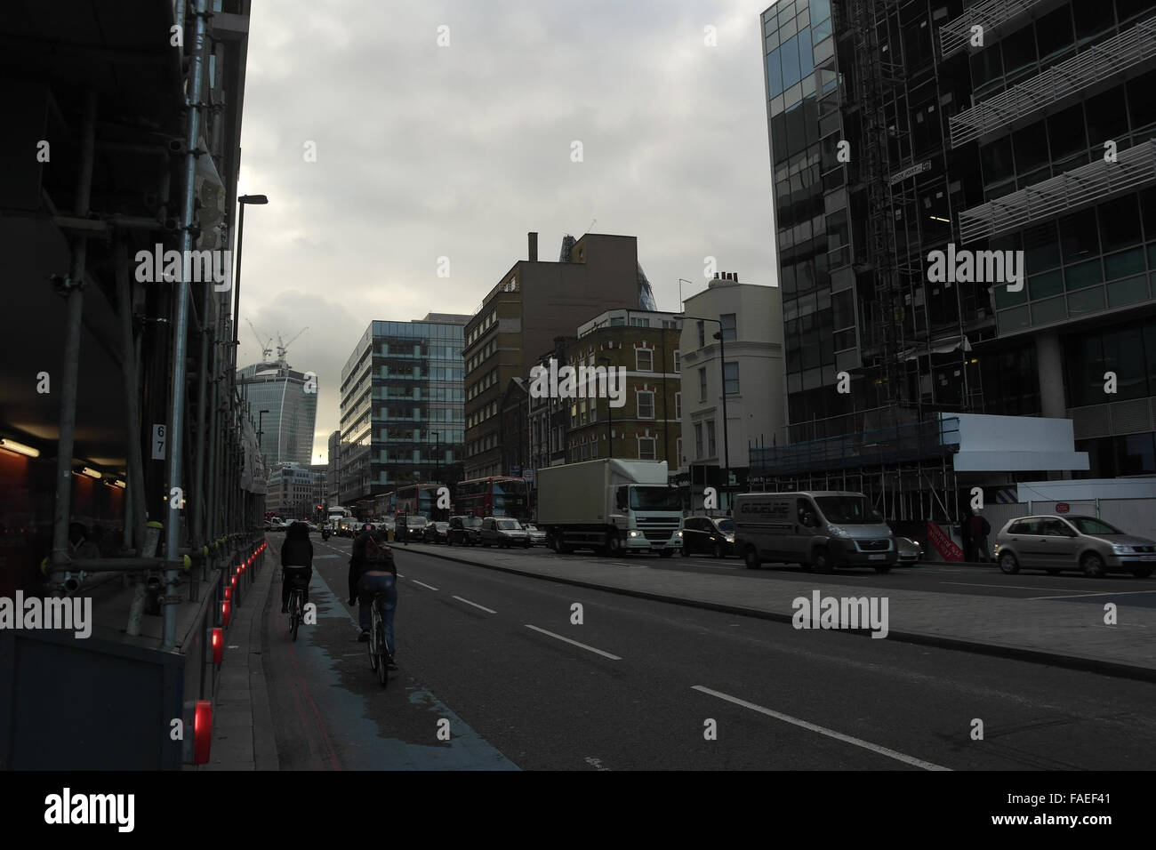 Nuvole grigie e vista della coda del traffico e i ciclisti passando le luci rosse ponteggio, Whitechapel Street a 20 Fenchurch Street, Londra Foto Stock