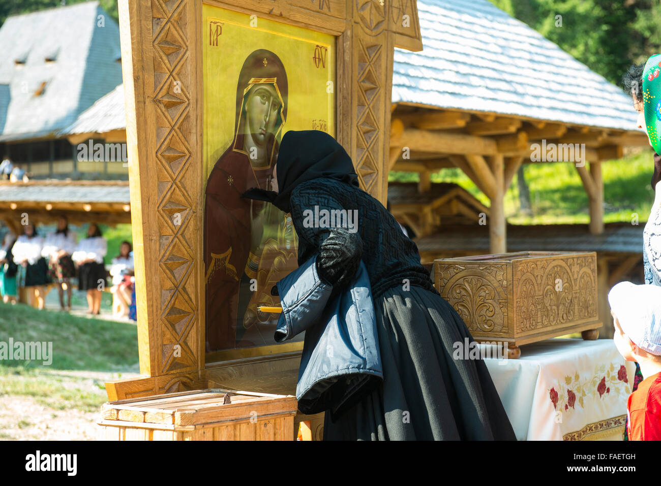 Una anziana signora baci un icona durante una funzione religiosa Foto Stock