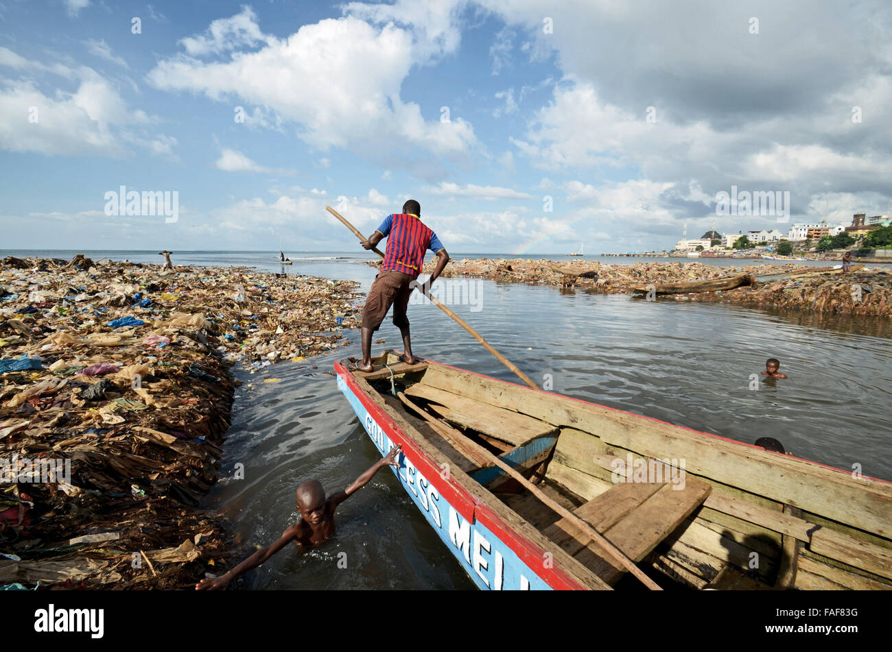 Uomo sulla barca in una discarica per rifiuti in Kroo Bay, a Freetown, in Sierra Leone. Foto Stock