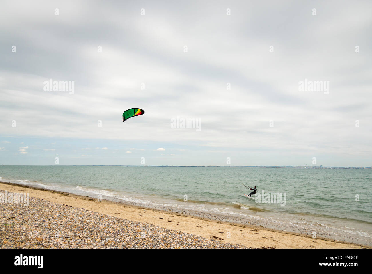 Un Kite Surf kitesurf sul mare e sull'Isola di Wight REGNO UNITO su un nuvoloso giorno Foto Stock