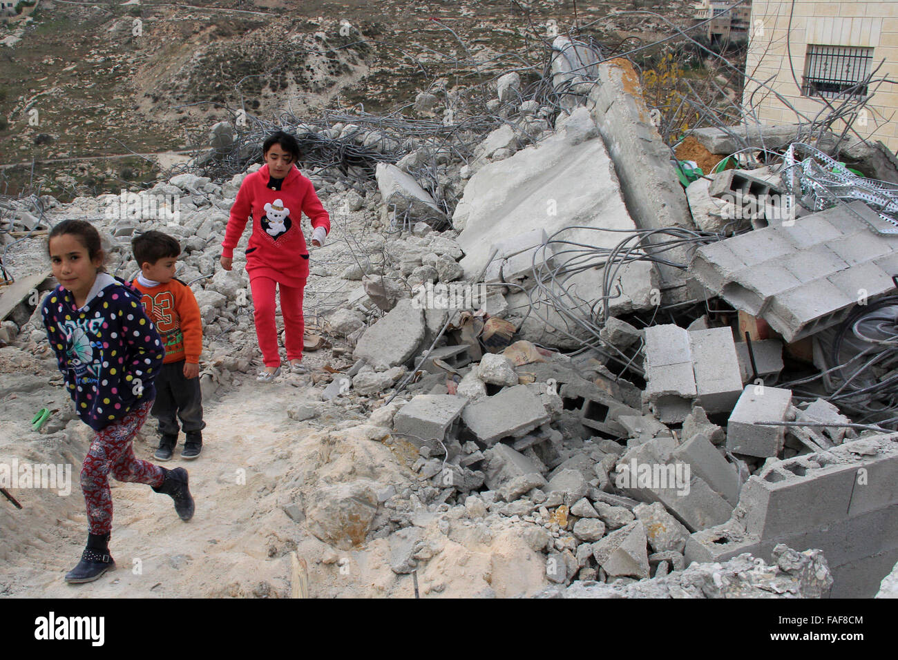 Gerusalemme, Territorio palestinese. 29 Dic, 2015. Bambini palestinesi stand sulle macerie della loro casa che fu demolita da Gerusalemme comune di lavoratori in Gerusalemme, Dicembre 29, 2015. Case palestinesi costruite senza un israeliano del permesso di costruzione sono spesso demolita per ordine del comune di Gerusalemme Credito: Mahfouz Abu Turk/immagini APA/ZUMA filo/Alamy Live News Foto Stock