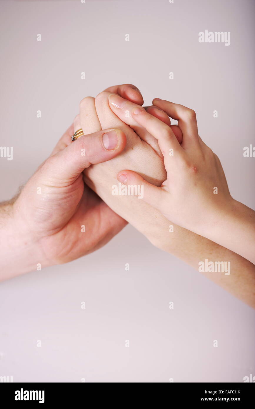 I giovani coniugi tenere le mani con i loro figli la mano appoggiata su ciascun genitore. Un momento di unità in un rapporto teso Foto Stock