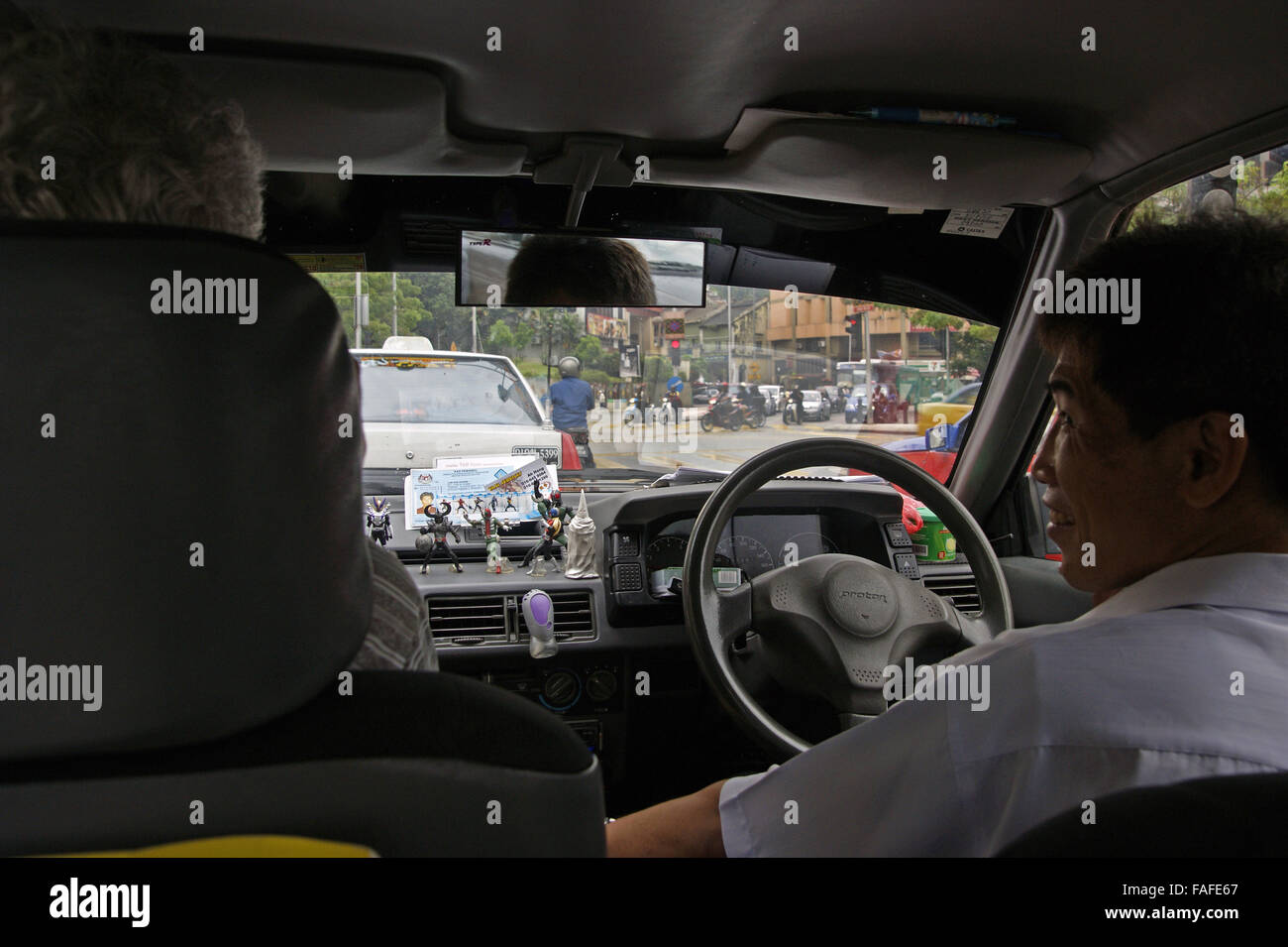 Taxi driver con dashboard giocattoli di Kuala Lumpur in Malesia Foto Stock