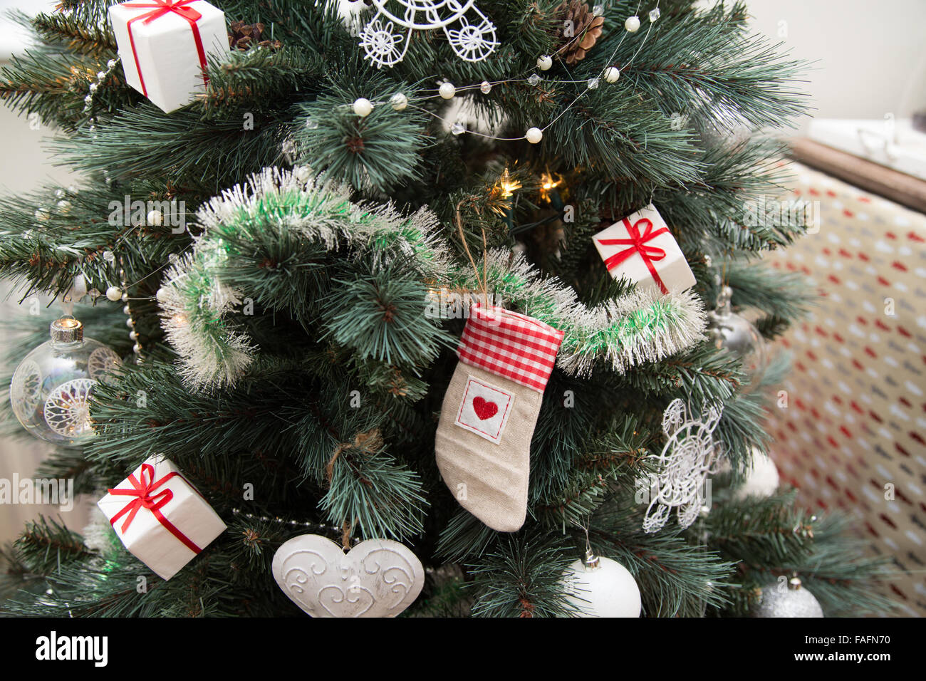 Natale abete con decorazioni pensili close up con calza baubles tinsel e presenta Foto Stock