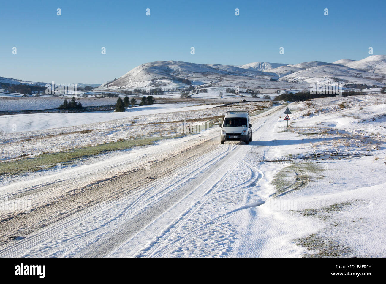 Auto su un683 vicino Kirkby Stephen che è coperto di neve, con Howgill Fells in background, Cumbria, Regno Unito. Foto Stock