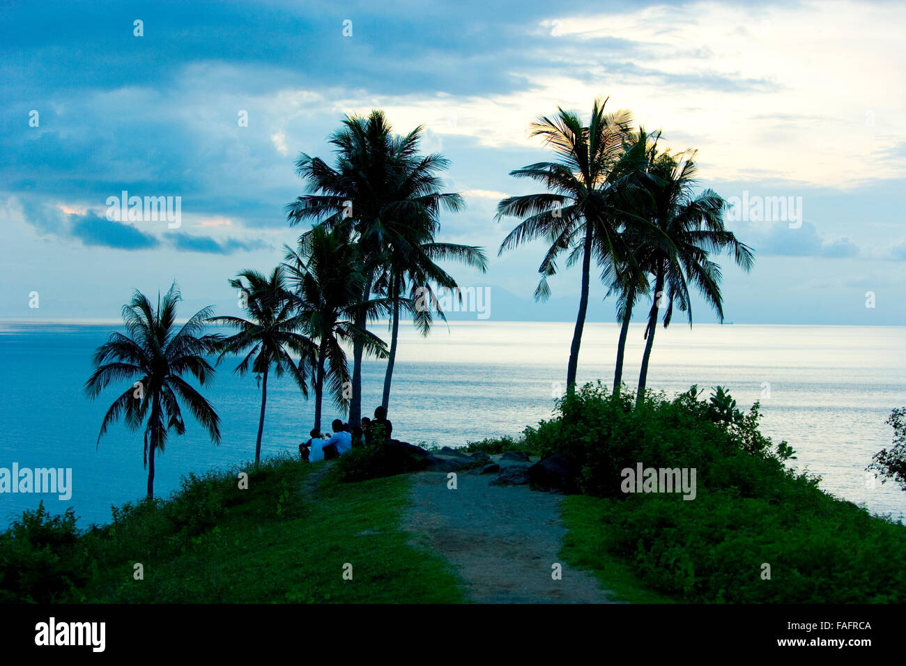 La gente a guardare il tramonto sotto le palme, Bali, Indonesia. Foto Stock