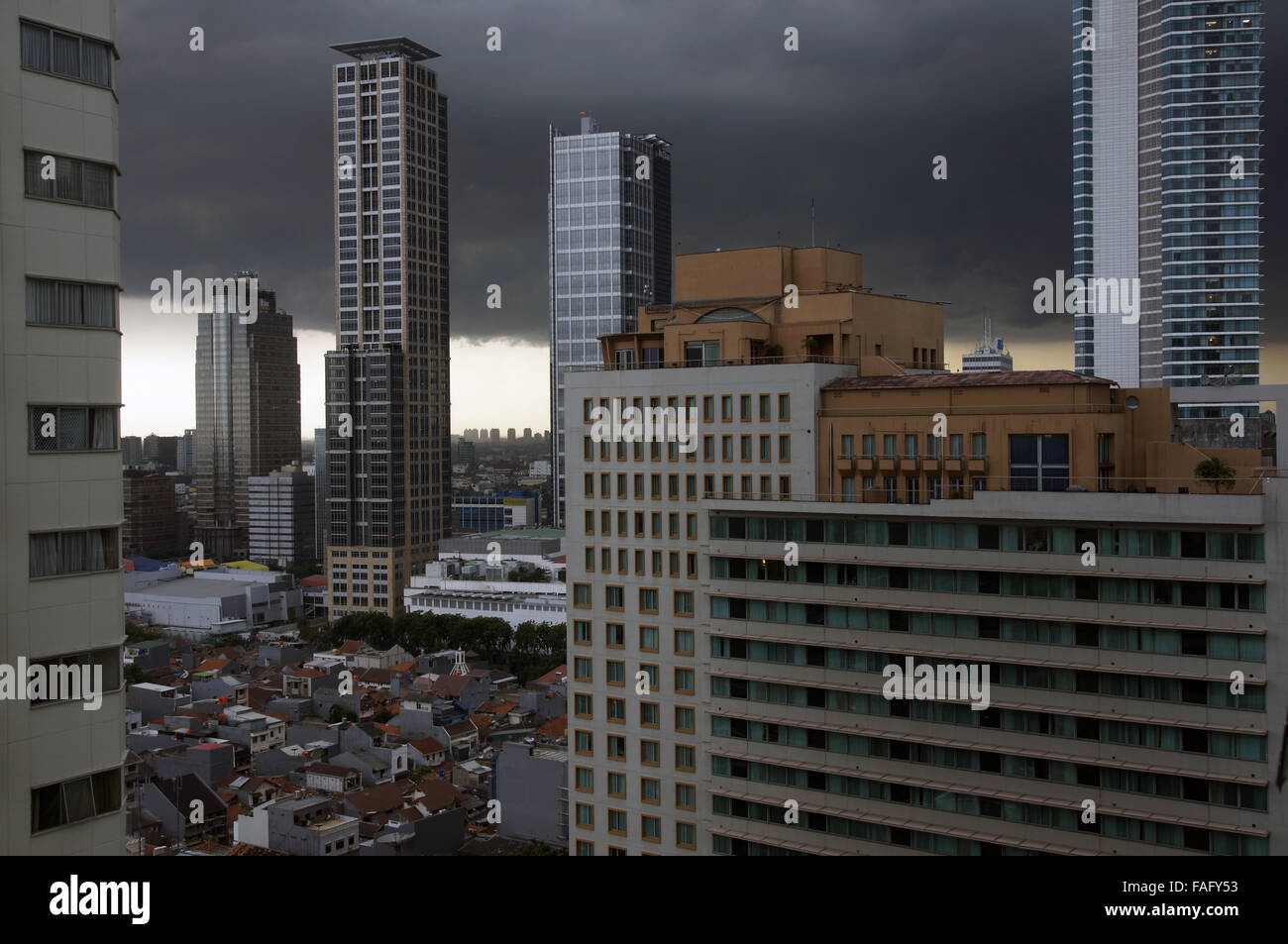 Heavy nuvole temporalesche fagocitare la torre della città e blocchi di edifici alti Foto Stock