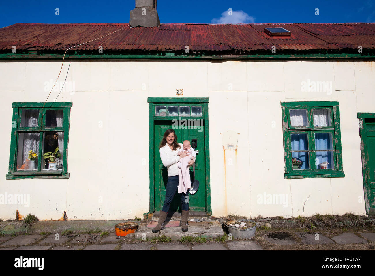 Madre con il suo bambino sta al di fuori di una delle case più antiche di Isafjordur, famoso per il modo in cui molti bambini sono nati in essa Foto Stock