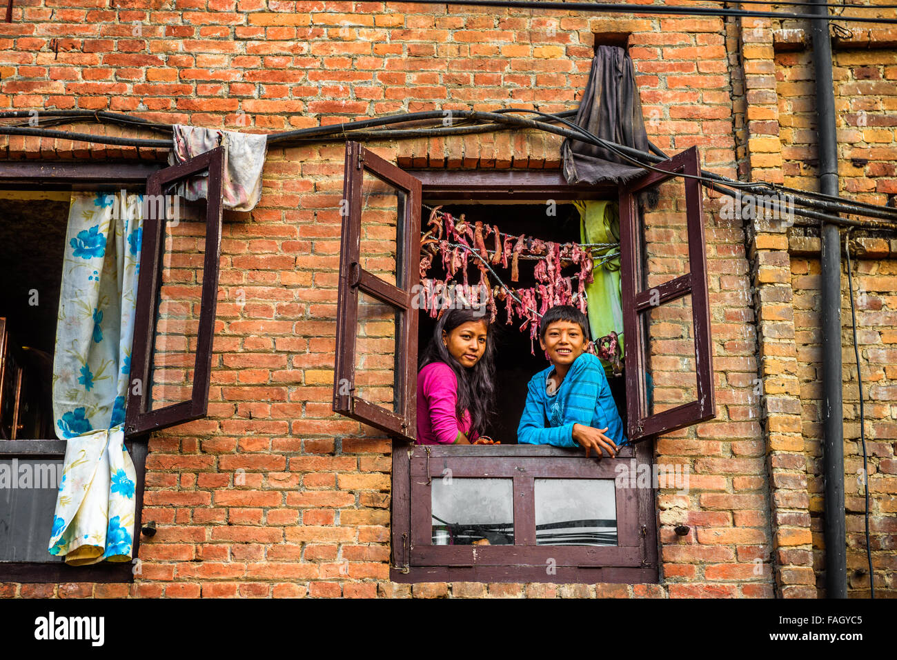 Due bambini sorridenti e guardando fuori della finestra in Nepal Foto Stock