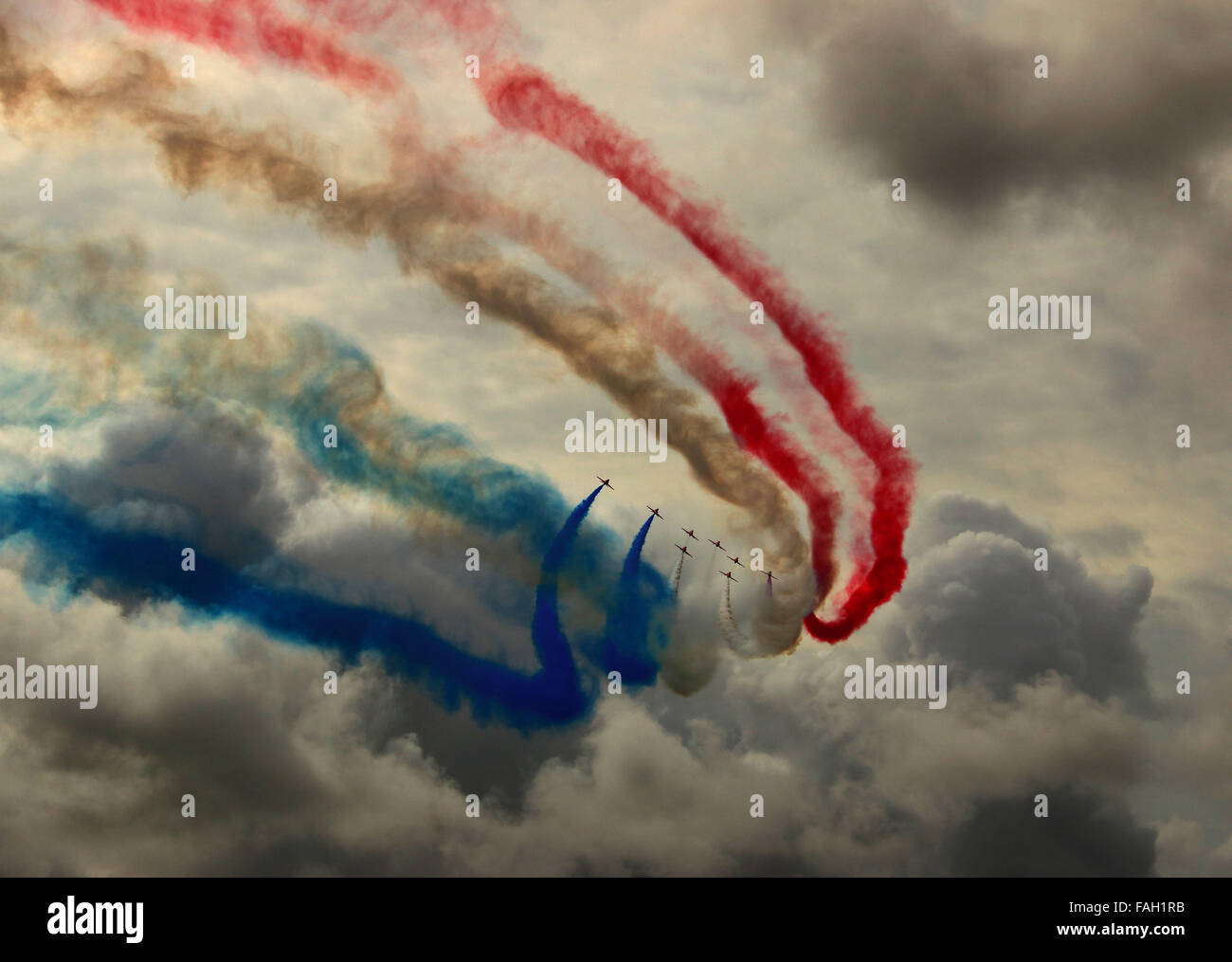 RAF frecce rosse Aerobatic Team Display dipingere un cielo tempestoso con rosso bianco e blu fumo. Foto Stock